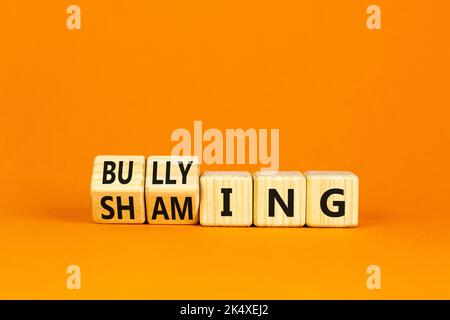 Shaming and bullying symbol. Concept words Shaming and Bullying on wooden cubes. Beautiful orange table orange background. Business shaming and bullyi Stock Photo