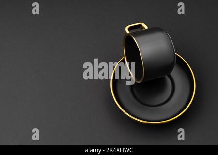 A Set of black and golden ceramic plates and cup on a black background Stock Photo
