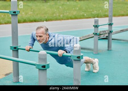 Full length portrait of active mature man doing push ups during outdoor workout in city Stock Photo