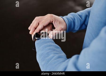 Close up of unrecognizable man setting up smartwatch against black background, copy space Stock Photo
