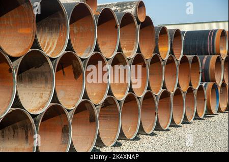 Lines of oilfield large streel pipes in an industrial construction area Stock Photo