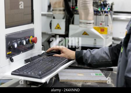 Operator controls computerized woodworking machine. Selective focus. Stock Photo