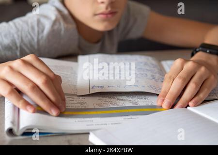 Kid affected by dyslexia doing homework, writing, reading notebook task using colorful overlay strip. Education, learning disability, reading Stock Photo