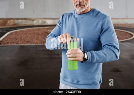 Cropped shot of unrecognizable senior man holding water bottle during outdoor workout in urban setting, copy space Stock Photo