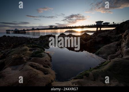 Sunrise on Llandudno Pier. With Victorian Promenade and sun rising behind Stock Photo