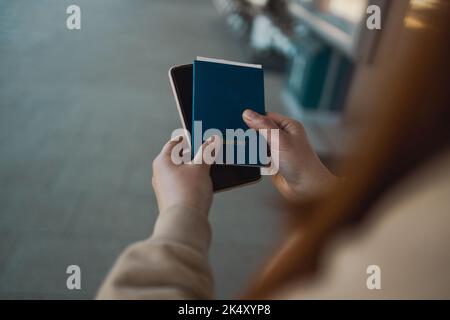 Closeup of girl holding passports, boarding pass and smart phone waiting for checking in an airport terminal for flight Stock Photo