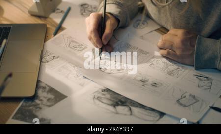 Closeup hands of a woman making pencil sketches. Working on a storyboard in a home based design studio. Woman drawing sketches as a roadmap for the video. Story telling. Stock Photo