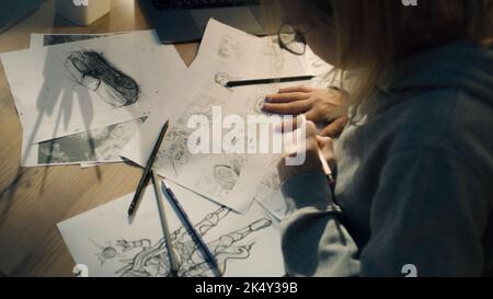 Female creative designer works on a storyboard and draws a sketches for a comic. Video editing, comics compilation, creative work concept. Stock Photo