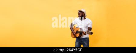 Full-length photo of excited artistic man playing his guitar. Isolated on yellow background. Stock Photo
