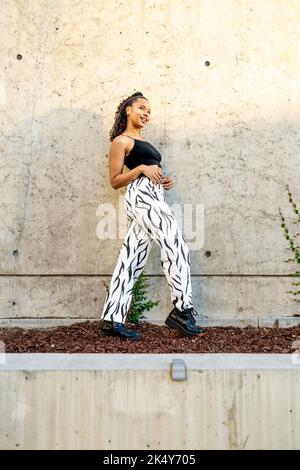Portrait of an Edgy Young Black Woman Standing in Front of a Concrete Wall Stock Photo