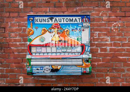 Germany, Lubeck - July 13, 2022: Multicolor funny Kustautomat artwork against red brick wall is totally fake automatic dispenser machine Stock Photo