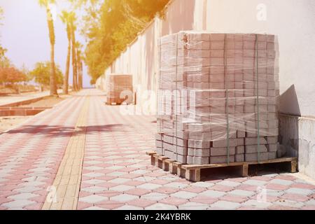 Paving stones on wooden pallet on the street sidewalk. Construction Paving of city streets and adjoining territories. Outdoor tile concrete paving blo Stock Photo