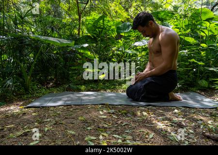 Young latin man arranging his yoga mat, inside a forest on a plain, direct contact with nature, mexico Stock Photo