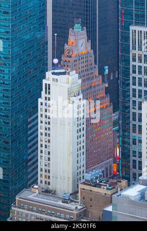 Manhattan highrise buildings, including 1501 Broadway, also known as the Paramount Building, a 33-storey office building on Times Square between West 43rd and 44th Streets in the Theater District of New York City. It was constructed from 1925 to 1927 as the headquarters of Paramount Pictures. The building is designed in the Art Deco style and has a distinctive rooftop clock. Stock Photo