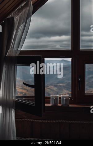 Two cups of tea on windowsill with opened window in front of mountains view Stock Photo