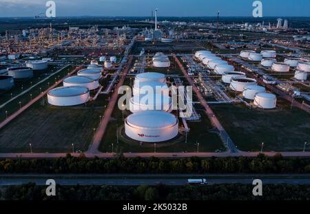 04 October 2022, Saxony-Anhalt, Leuna: Behind the illuminated tank farm, the facilities of the Total refinery and the chemical park rise into the air (aerial view with drone). The refinery, built in 1997 by the French mineral oil company Elf-Aquitaine, is celebrating its 25th anniversary on the same day. Around 12,000 people work in various companies at the 1300-hectare chemical site in Leuna, including around 600 in the refinery. Every year, gasoline, diesel, heating oil, liquefied petroleum gas, aviation fuels, bitumen, methanol and other specialty chemical products are produced here from up Stock Photo