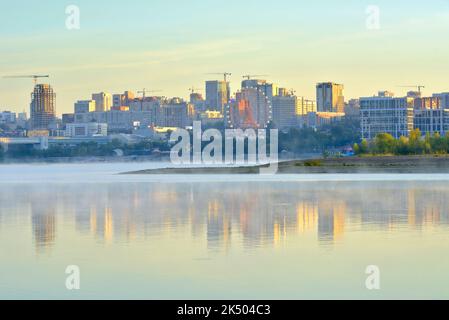 Novosibirsk, Siberia, Russia, 09.03.2022. The city on the Ob in the morning. Houses on the river embankment are reflected in the water in a blue fog Stock Photo