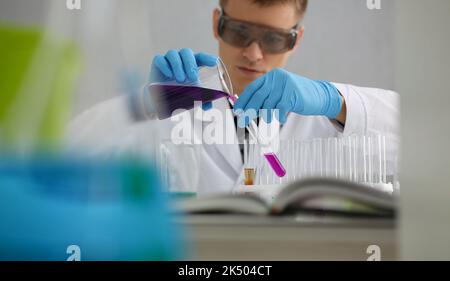 Scientist in protective gloves holding test tube of purple liquid Stock Photo