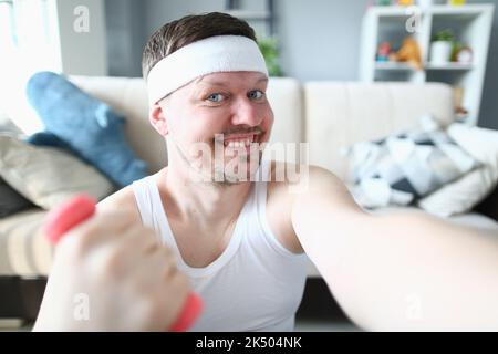 Young handsome muscular athletic young man taking selfie photo lifting dumbbells Stock Photo