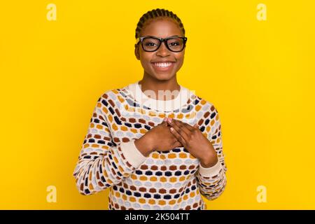 Portrait of cheerful friendly lady hands touch heart toothy smile thankful isolated on yellow color background Stock Photo