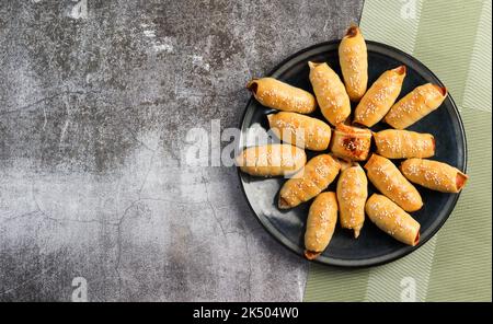 Sausage Bread Rolls  on a round plate on a dark grey background. Top view, flat lay Stock Photo