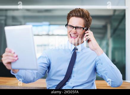 I am super impressed with this. An excited businessman taking a call and looking at his tablet screen. Stock Photo