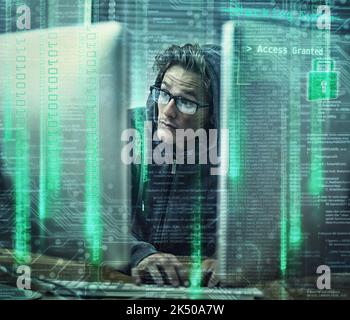 Hacking the main frame. a young man wearing hoodie while hacking into a computer. Stock Photo
