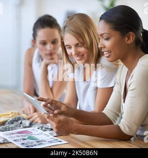 Great creative minds think alike. Three pretty young fashion designers discussing a design and smiling. Stock Photo