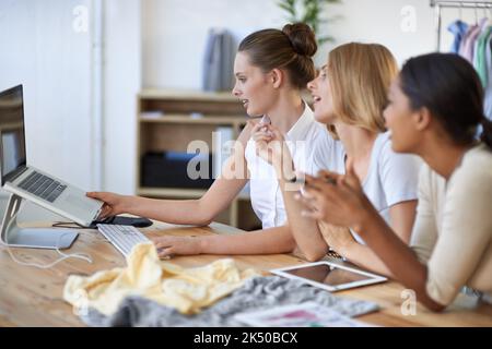 What do you guys think about this design. Three young fashion designers having a discussion while looking at a laptop. Stock Photo
