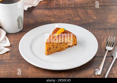 Delicious carrot cake with coffee next to it on wooden table Stock Photo