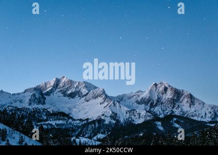 A scenic view of Mountain Sneffels covered with pine forests and snow at starry night in Chicago Stock Photo
