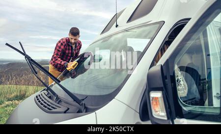 Man cleaning camper van windshield outdoor Stock Photo