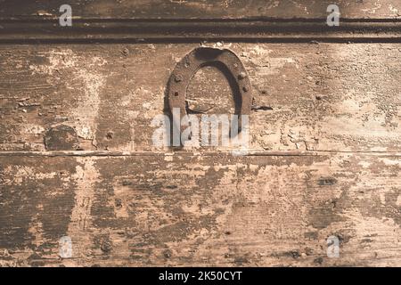 ancient wooden door fragment with focus on nailed rusty horseshoe Stock Photo