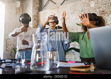 Office creative entrepreneurs having a 3d business meeting in the metaverse cyberspace - group of multiethnic colleagues wearing vr goggles headset an Stock Photo