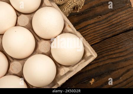 White chicken eggs in a cardboard box on the table. Close-up, selective focus Stock Photo