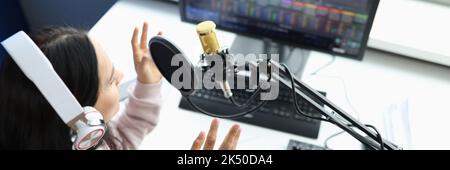 Woman in headphones in front of microphone broadcasts radio Stock Photo