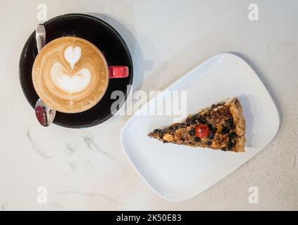 A slice of Ecclefechan Tart on a white plate with a cup of flat white coffee Stock Photo