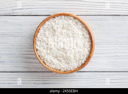 Coconut flakes in wooden bowl on white wooden background Stock Photo