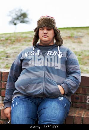 Its never too cold for a smoke break. An obese man sitting outside smoking a cigarette on a winters day. Stock Photo