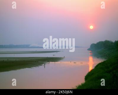 Laos: Fishermen and river weed collectors work as the sun sets over the Mekong River near Vientiane. The River Mekong is the world's 12th-longest river. From its Himalayan source on the Tibetan plateau, it flows some 4,350 km (2,703 miles) through China's Yunnan province, Burma, Laos, Thailand, Cambodia and Vietnam, finally draining in the South China Sea. Stock Photo