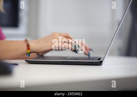 Woman with long nails typing text on laptop keyboard Stock Photo