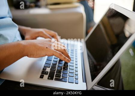 Hands typing on laptop, sitting on sofa at university and studying online. Student on social media, research school project or writing email on couch Stock Photo