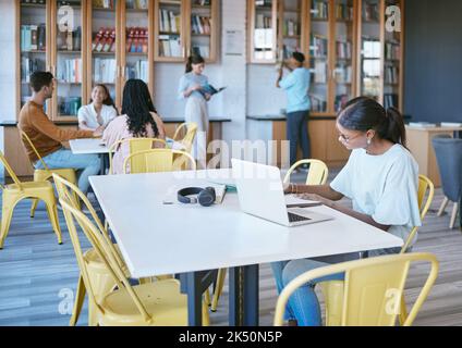 Studying, library and student in university writing ideas in notebook, planning research strategy on laptop for course work. Community, education and Stock Photo