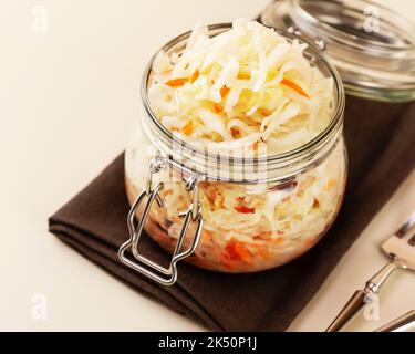 Sauerkraut in glass jar on a brown napkin with fork and knife Stock Photo