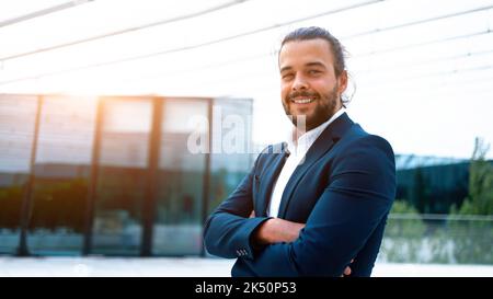 Successful businessman suit with beard standing in front of office glass building arm crossed confidently looking in camera and smile. Hispanic male business person portrait. Web banner, Free space Stock Photo