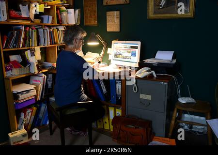 mature lady working from home at desktop computer Stock Photo