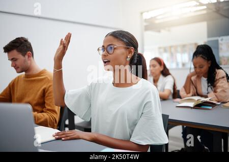 Education through questions by students at university with diversity during lecture. Young woman in classroom, asking with hand up while classmate Stock Photo