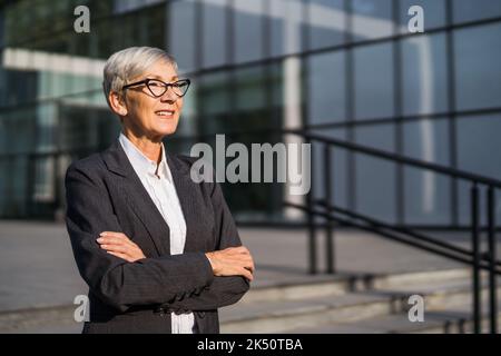 Outdoor portrait of successful senior businesswoman in front of company building. Stock Photo