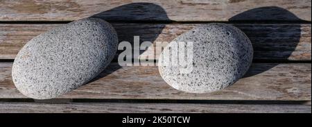 Finnish round sauna stones with a shadow on a wooden plank background Stock Photo