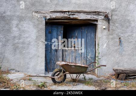 Old Barn Door and Rusty Wheelbarrow Stock Photo